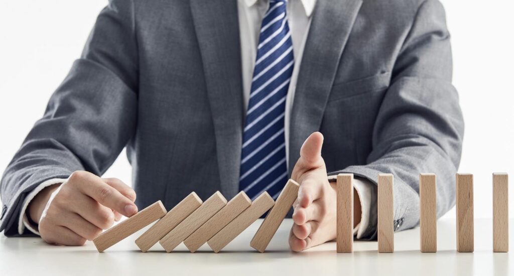 businessman protecting from domino effect