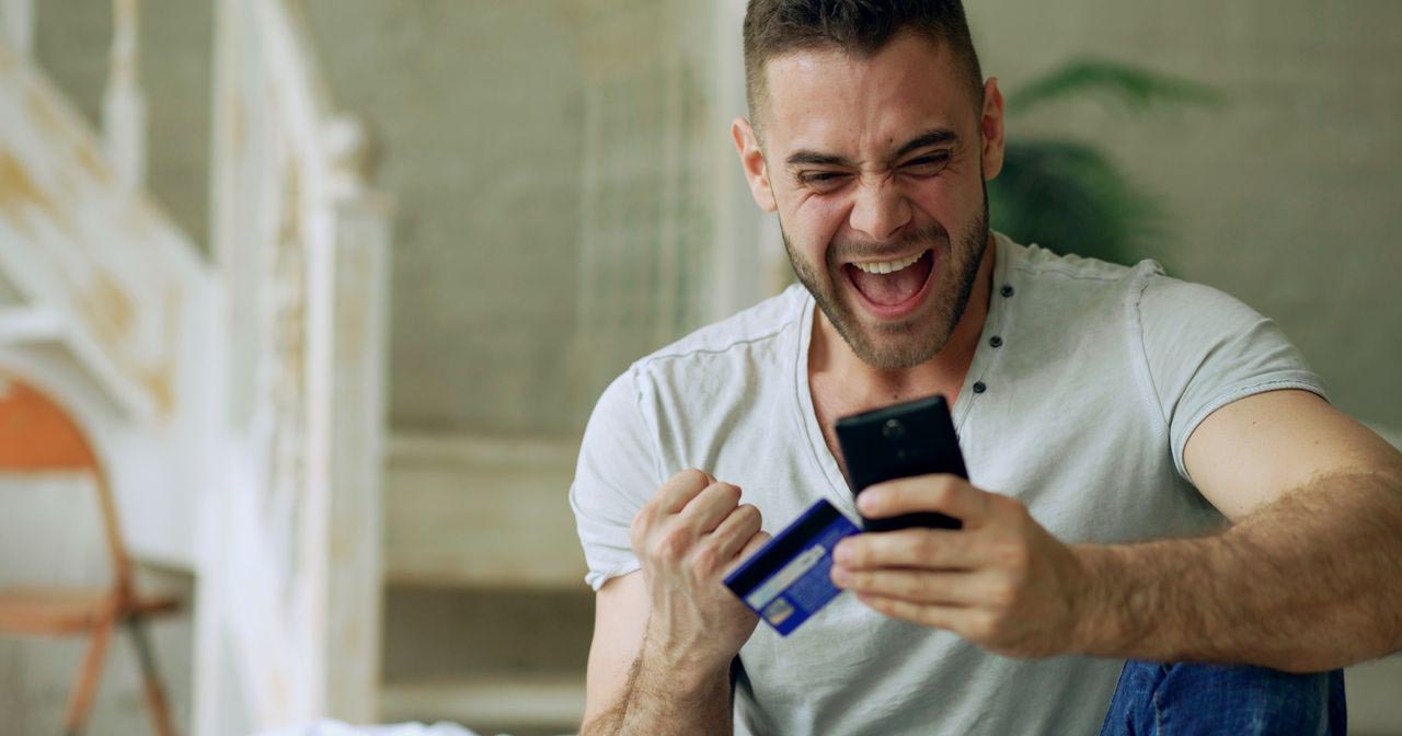 excited man with smartphone and credit card