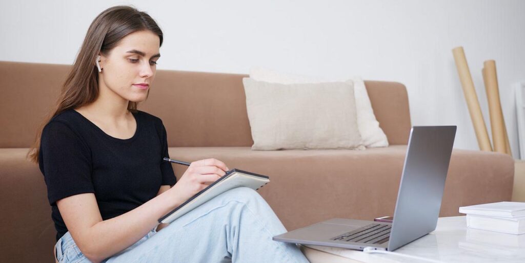 young entrepreneur watching online taking notes